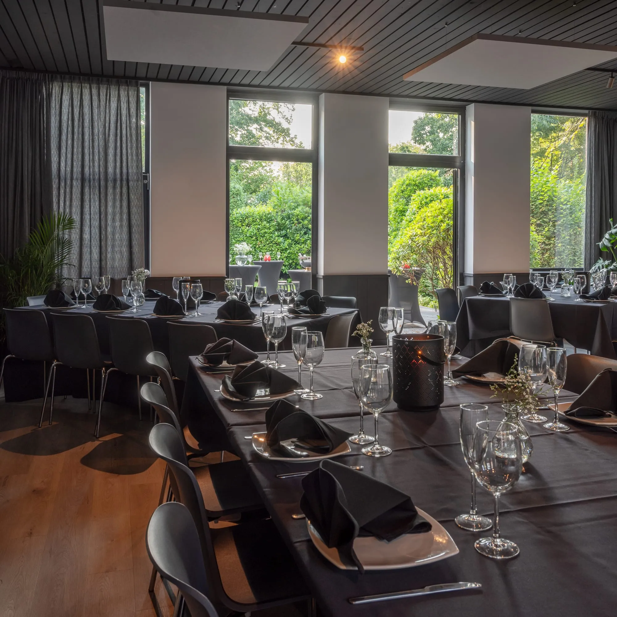 La salle de Sainte-Anne dressée pour un repas, grandes baies vitrées ouvertes sur le jardin